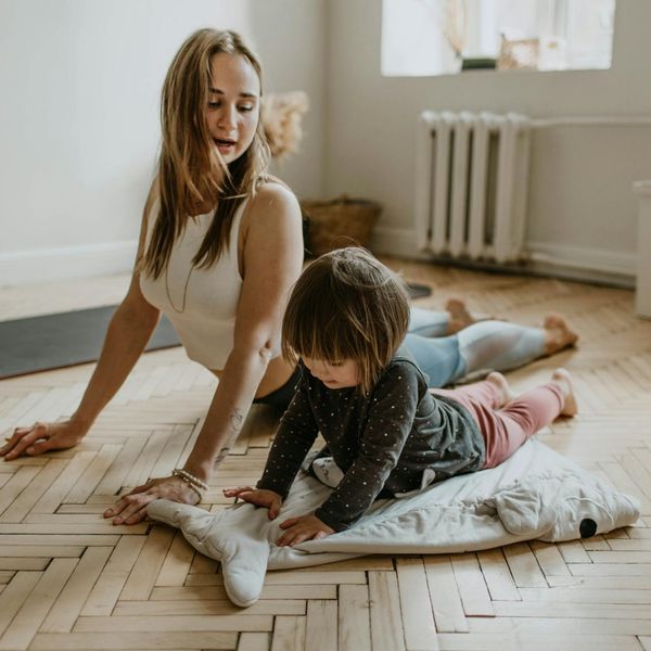 Happy child in a playful yoga tree pose in a sunlit room.